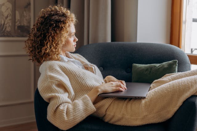 freelancer on sofa writing on a laptop