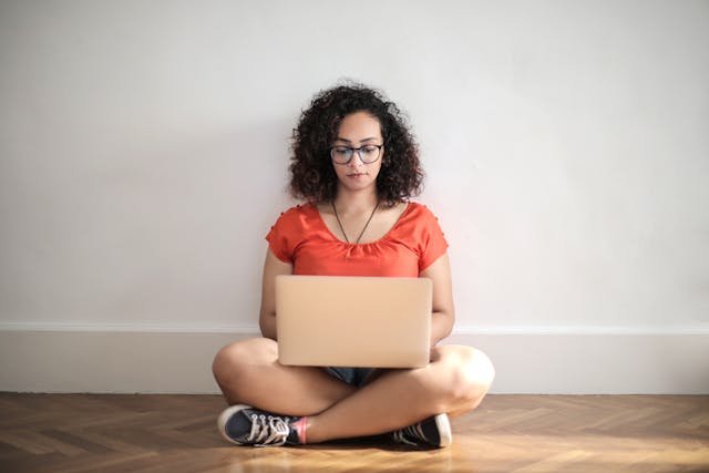 freelancer sitting on a floor with laptop on her lap