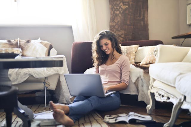 freelancer sitting on the floor writing on a laptop