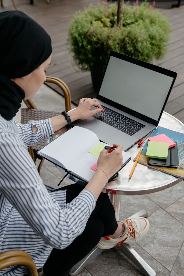 freelancer writing on a book with laptop