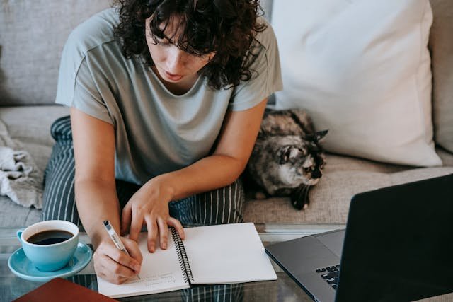 freelancer sitting on a couch writing on her notebook